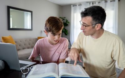 Photo of a son and father looking at a textbook to illustrate the article 