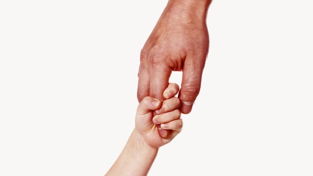 Photo of a father's hand holding a small child's hand to illustrate the article Fumbling Through Parenthood: What Becoming a Dad Has Taught Me About God