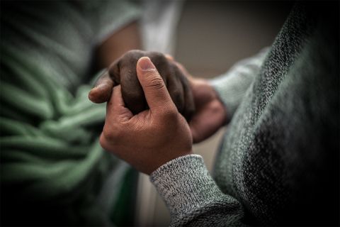 Two people clasping hands in grief and comfort to illustrate the article The Art of Dying Well