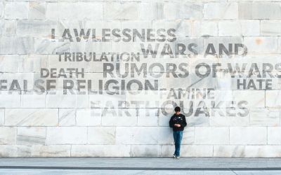 Person standing in front of a large wall displaying negative words associated with the end times, to illustrate the article 