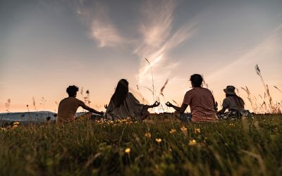 Photo of people sitting in a field facing the sun to illustrate the article Is the Law of Attraction Biblical?