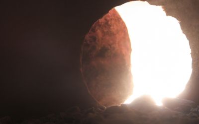 View from inside a tomb looking toward a round opening with the round stone door mostly rolled back. This illustrates the article 